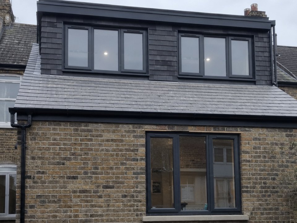 Rear of a stock brick terrace with a slate hung loft dormer