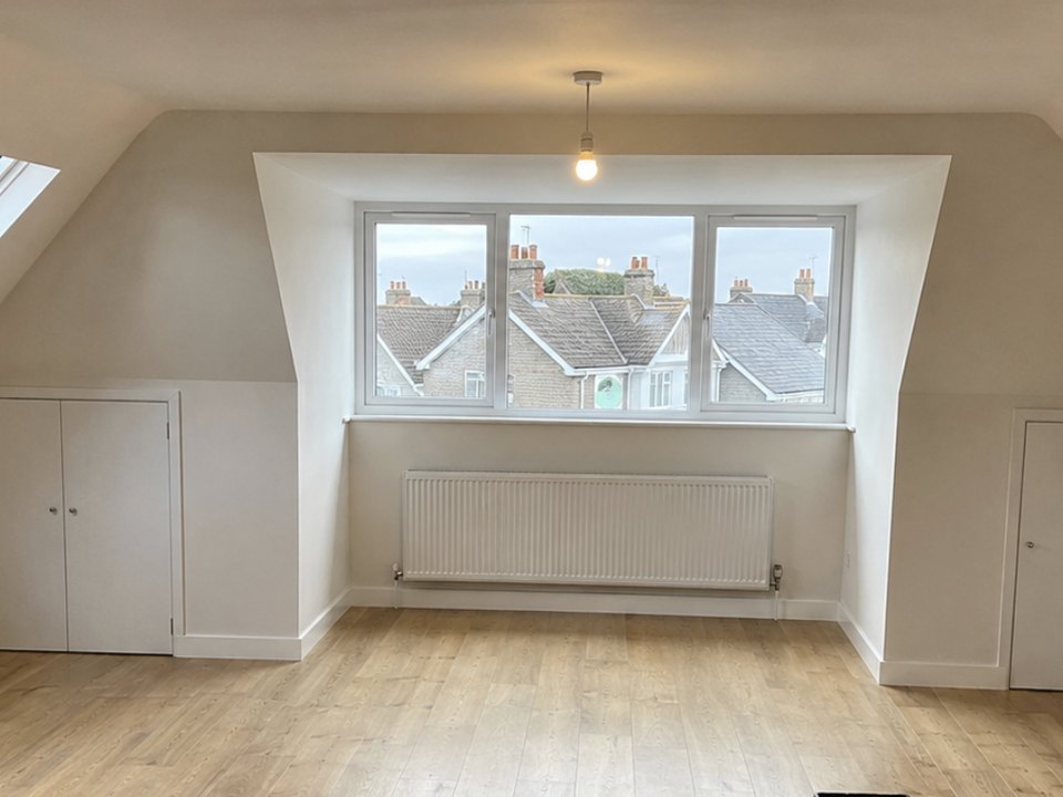 Finished loft bedroom with a dormer window and fitted wardrobes
