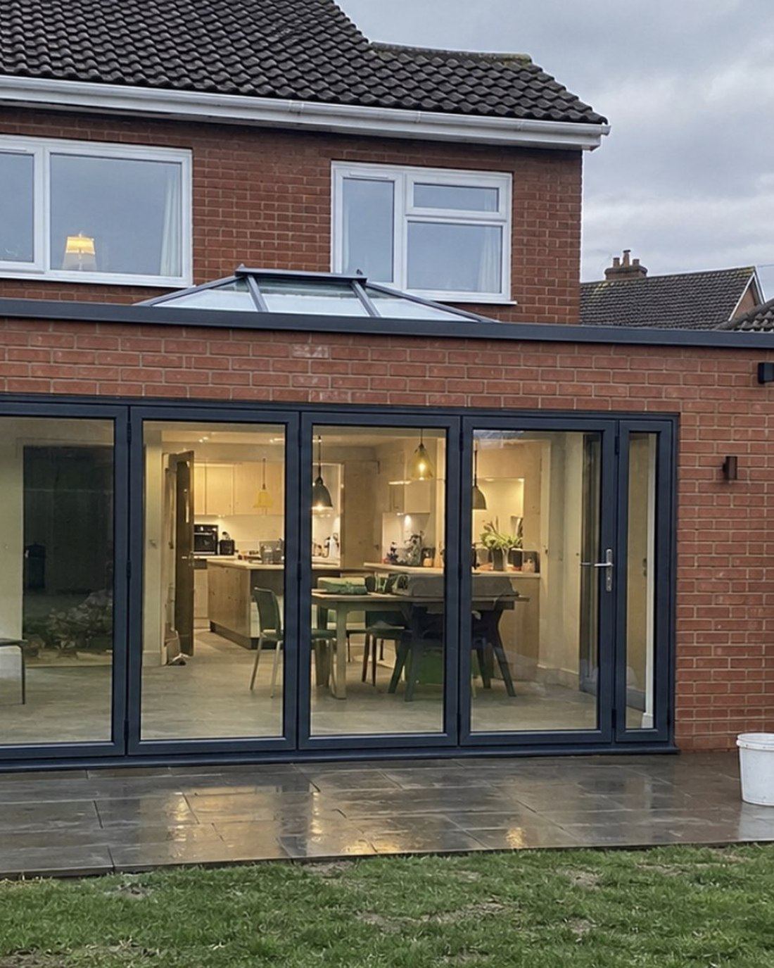 Finished brick rear extension lit at dusk with a roof lantern and bifold doors